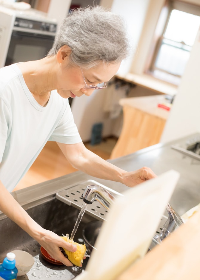 高齢の女性が流しで洗い物をしている様子